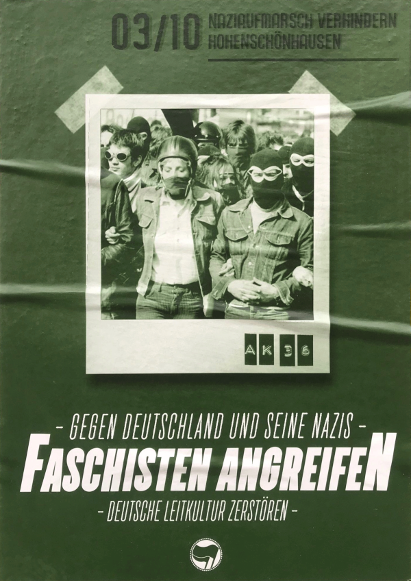 Ein grünes Plakat zeigt ein Schwarz-Weiß-Foto einer Menschenmenge mit Schutzbrillen und Masken. Der Text lautet "03/10 Naziaufmarsch verhindern Hohenschönhausen" und "Gegen Deutschland und seine Nazis Faschisten angreifen Deutsche Leitkultur zerstören."