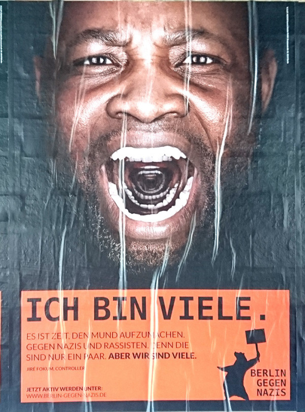 Nahaufnahme des Gesichts eines Mannes mit offenem Mund und einem Schrei. Das Plakat hat einen orangefarbenen Abschnitt mit Text: "Ich bin viele. Es ist Zeit, den Mund aufzumachen. Gegen Nazis und Rassisten. Denn die sind nur ein paar. Aber wir sind viele." Darunter: "Jetzt aktiv werden unter: www.berlin-gegen-nazis.de" und eine Silhouette, die ein Schild mit "Berlin gegen Nazis" hält.