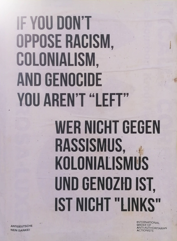 Ein Poster mit weißem Hintergrund und schwarzem Text. Oben steht: "If you don’t oppose racism, colonialism, and genocide you aren’t 'left'". Darunter die deutsche Übersetzung: "Wer nicht gegen Rassismus, Kolonialismus und Genozid ist, ist nicht 'links'". Unten links steht klein "Antideutsche Nein Danke!", rechts unten "International Order of Anti-Authoritarian Actionists".