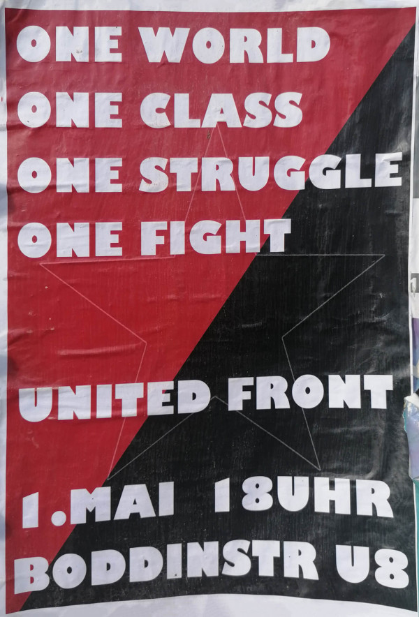Plakat mit rotem und schwarzem Hintergrund, diagonal geteilt. Text in weißer, fetter Schrift: "One World One Class One Struggle One Fight." Darunter steht "United Front" und "1. Mai 18 Uhr Boddinstr U8". Im Hintergrund ist der Umriss eines Sterns in der Mitte zu sehen.
