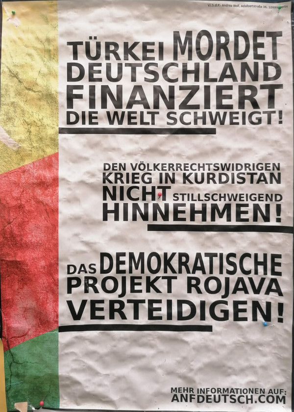 Ein Poster mit weißem Hintergrund und schwarzem Text. Oben steht: „Türkei mordet, Deutschland finanziert, die Welt schweigt!“. Darunter: „Den völkerrechtswidrigen Krieg in Kurdistan nicht stillschweigend hinnehmen!“. Weiter unten: „Das demokratische Projekt Rojava verteidigen!“. Links zeigt das Poster vertikale Streifen in Gelb, Rot und Grün. Unten rechts steht: „Mehr Informationen auf: anfdeutsch.com“.