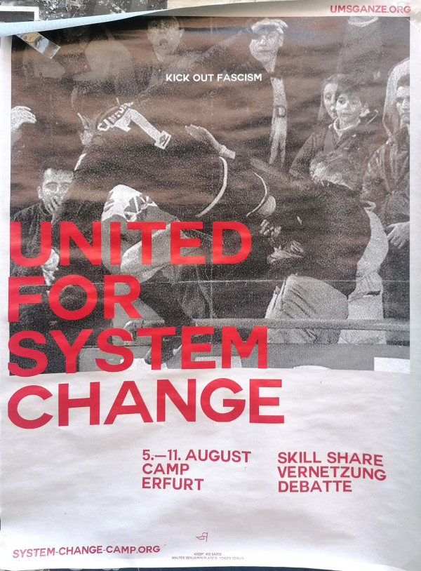 Ein Poster mit einem grobkörnigen Schwarz-Weiß-Foto von Menschen im Stadion. Ein Fußballspieler springt mit gestrecktem Bein gegen einen Zuschauer. Oben steht "Kick Out Fascism". In großer roter Schrift steht "United for System Change". Unten sind die Details "5.-11. August Camp Erfurt" und "Skill Share Vernetzung Debatte" ebenfalls in Rot. Oben rechts ist die URL "umsganze.org" und unten "system-change-camp.org".